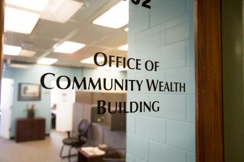 Glass office door with "Office of Community Wealth Building" lettered